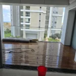 רצפת עץ כהה ומצוחצחת ליד חלון עם דלי, באמצע העבודה