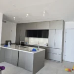 אי מטבח לבן עם צינור שואב על הרצפה במהלך הניקיון