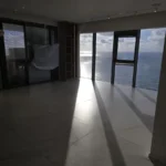 חדר ריק ומואר באור שמש עם חלונות גדולים, נקי למסירה